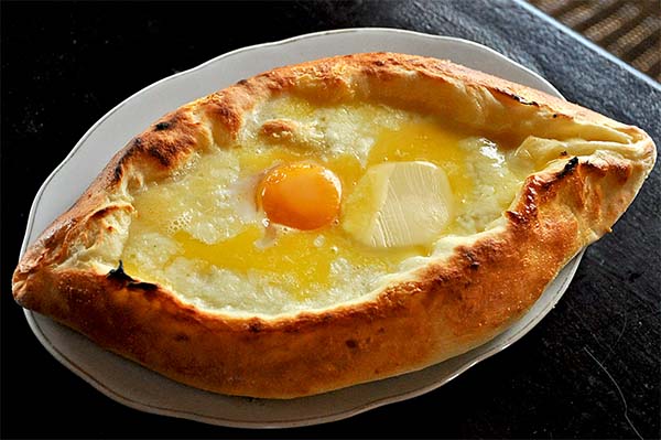 Chaczapuri na talerzu, widać ser w cieście na środku surowe żółtko jaja