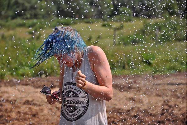 dziewczyna z mokrymi niebieskimi włosami kuli się przed kroplami wody